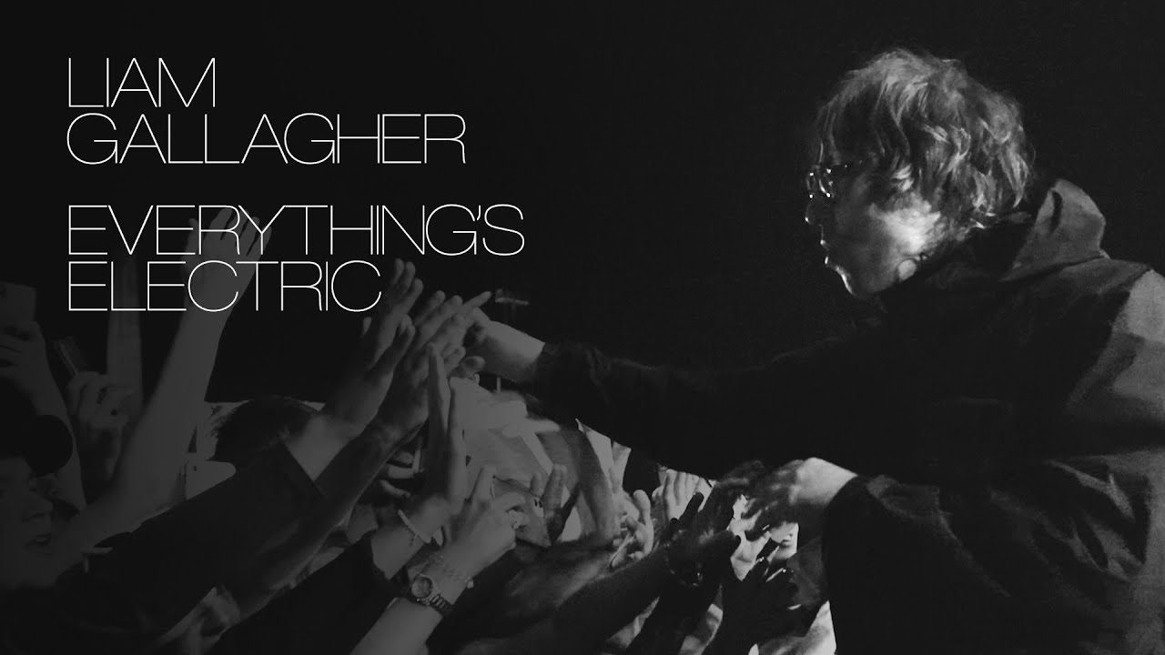 Liam Gallagher is pictured in black and white approaching a crowd during one of his performances. Text is overlaying the image and reads "Liam Gallagher, Everything's Electric".